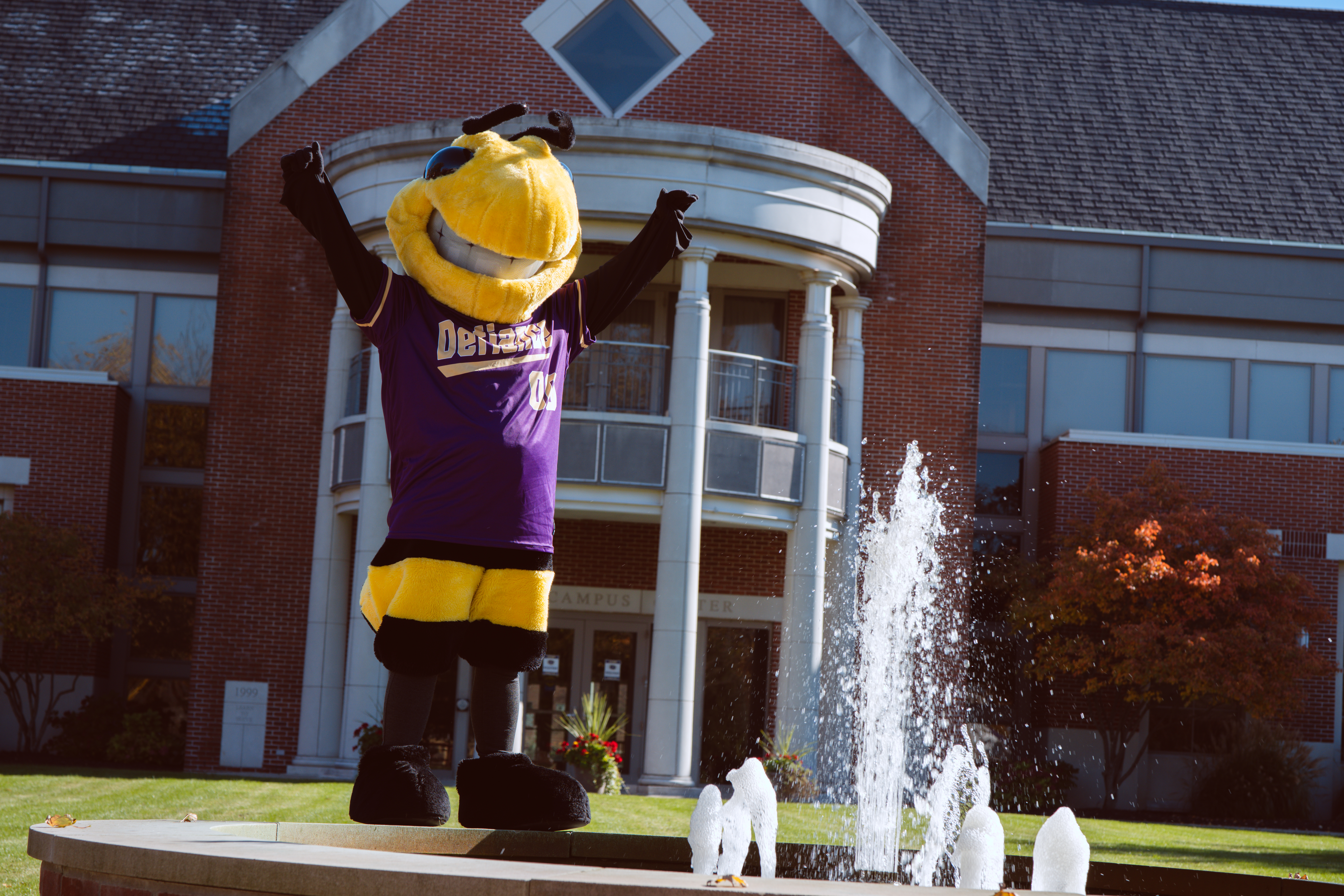 defiance college mascot standing in front of serrick center on fountain
