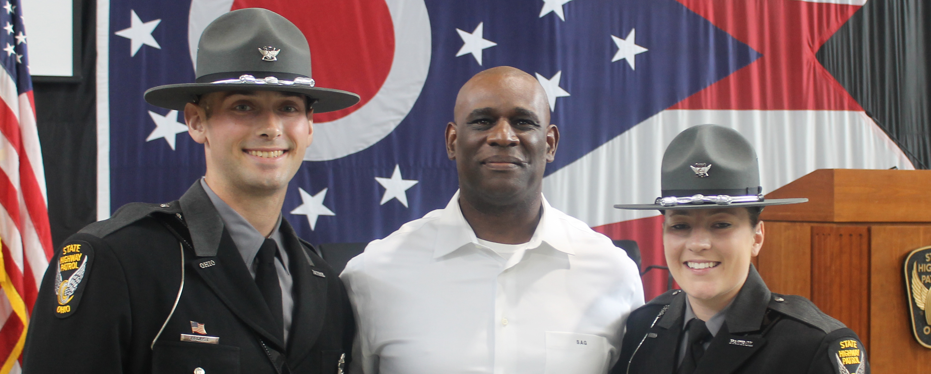 Professor Goodrum standing with two program graduates in full State Highway Patrol uniform and smiling at the camera