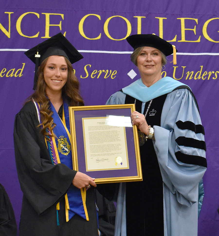 Ely King holding a framed award next to Defiance College President Richanne Mankey