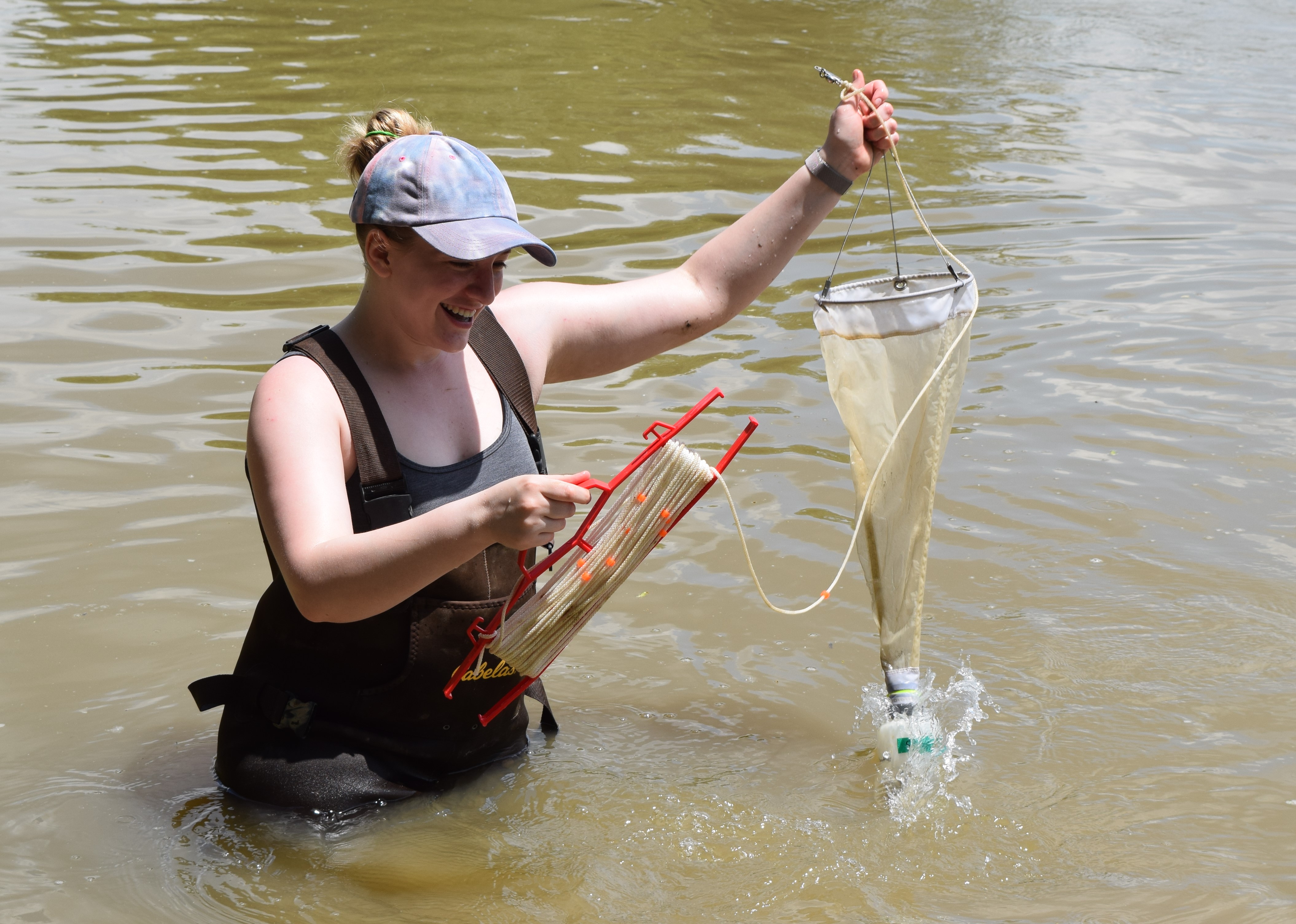 female student with net in water gather samples