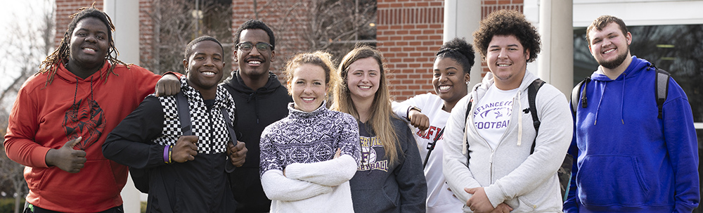 8 students standing together and smiling at the camera