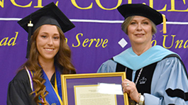 Ely King holding a framed award next to Defiance College President Richanne Mankey