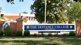 Purple and gold balloons around Defiance College sign