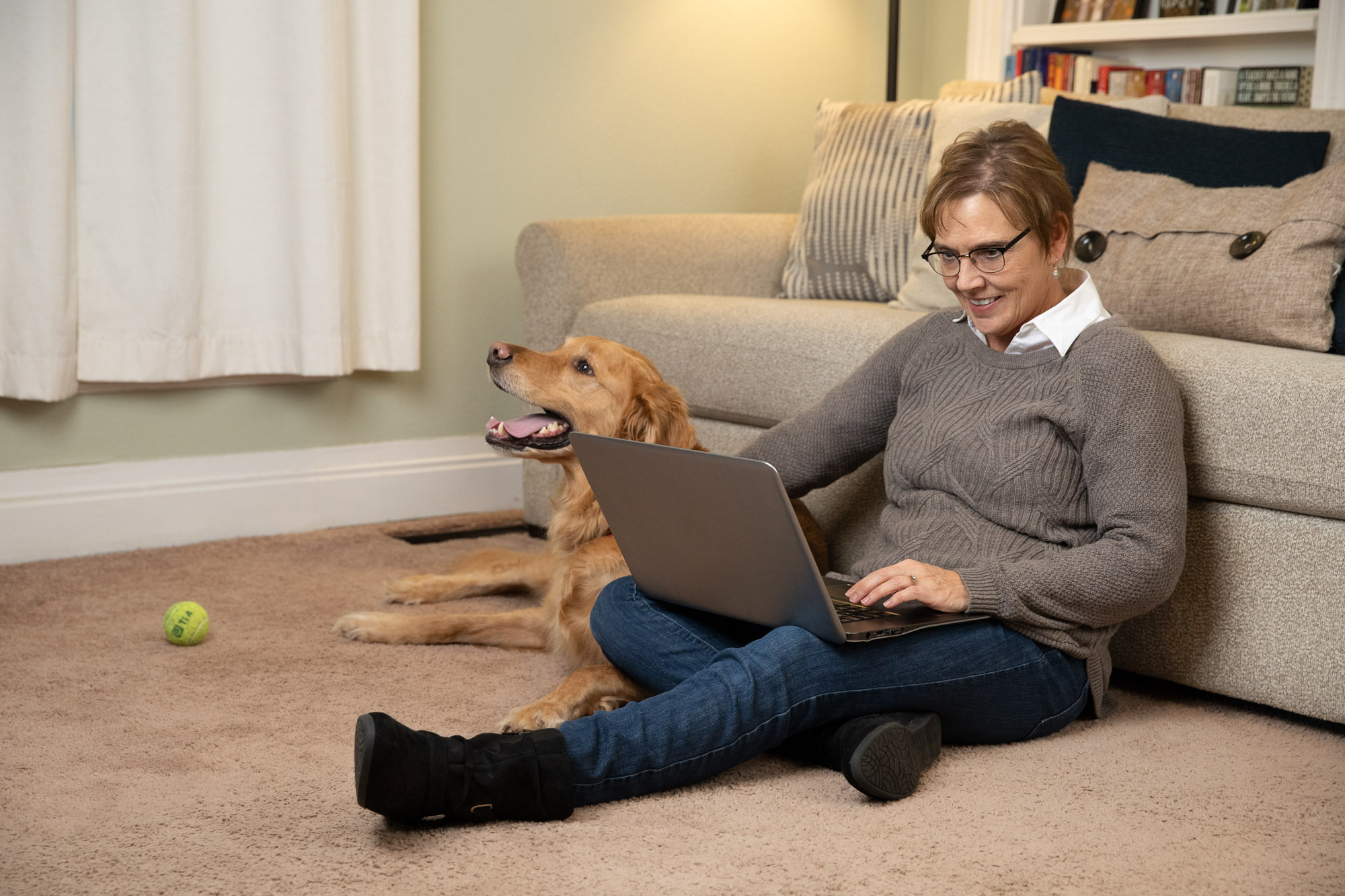 woman at computer with dog by her side