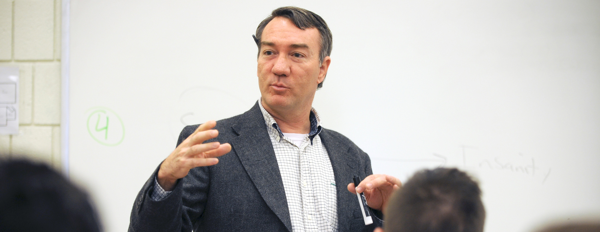 male professor speaking in front of a whiteboard