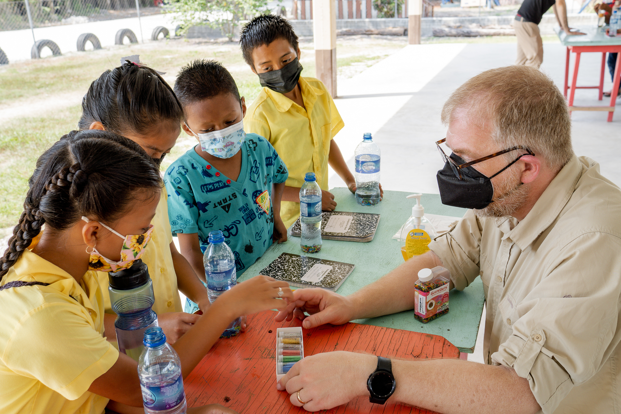 A man assisting young students with crafts