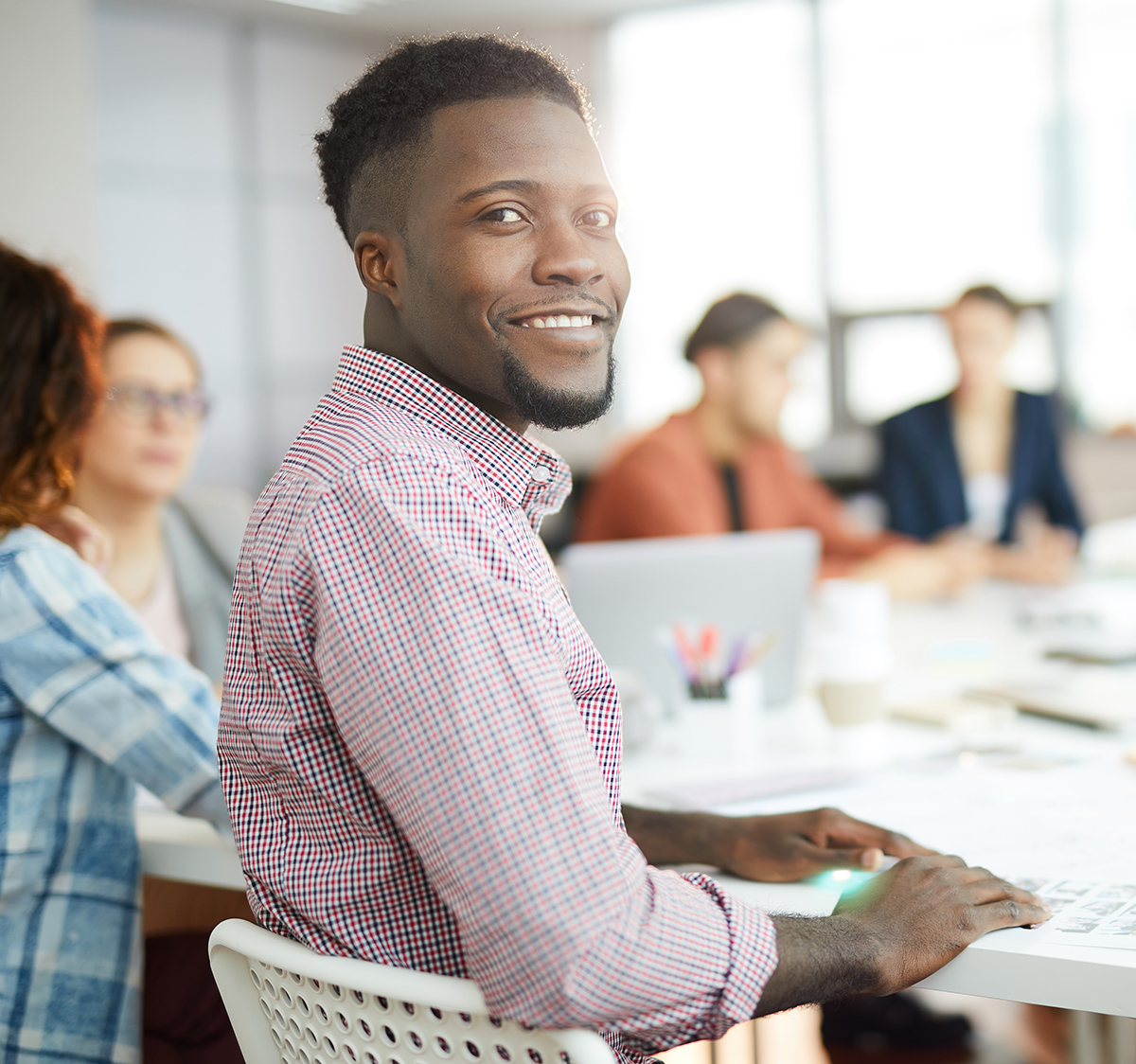 man sitting at a conference table looking over his shoulder and smiling at the camera