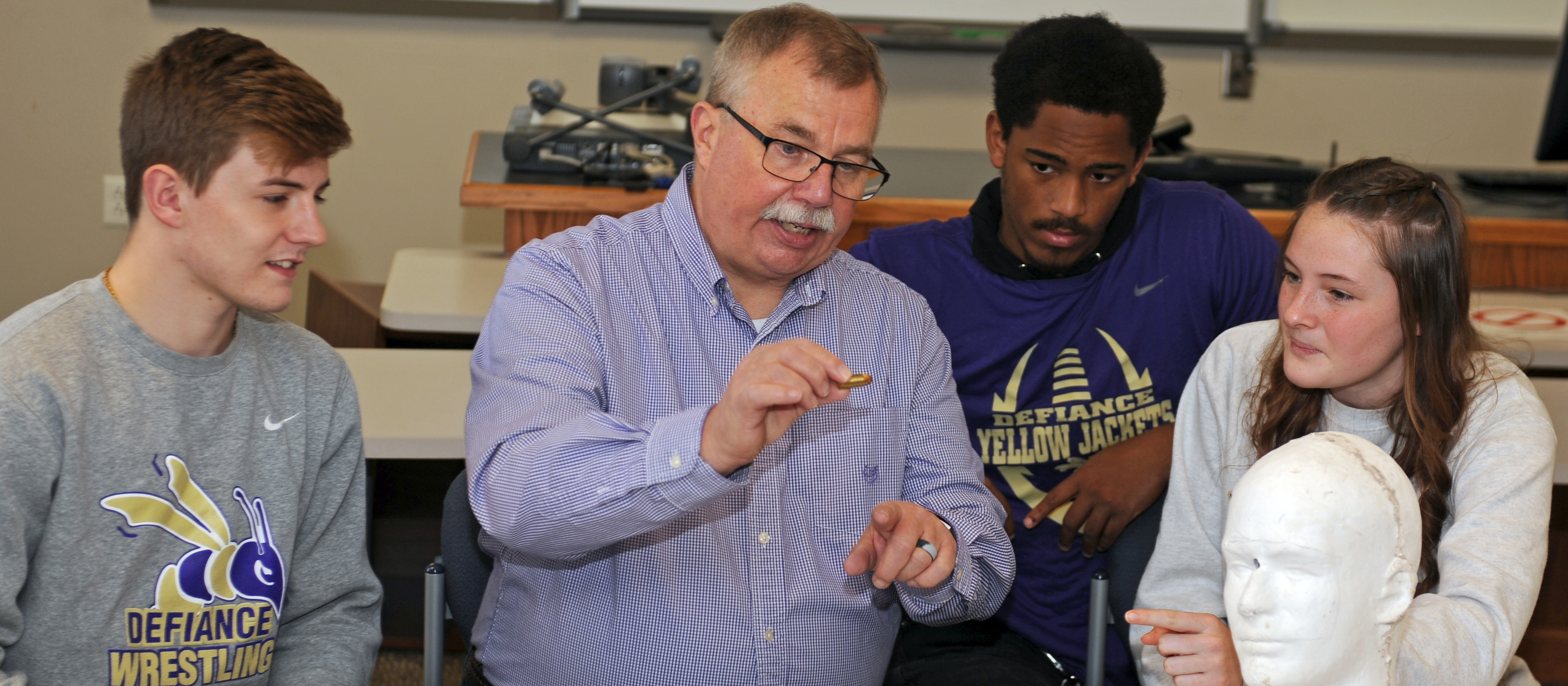 Professor Goodrum standing with two program graduates in full State Highway Patrol uniform and smiling at the camera