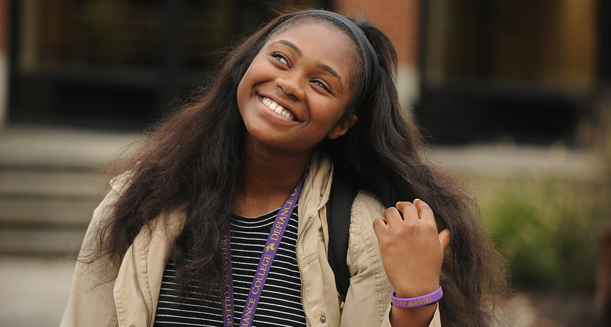 Female student with long black hair smiling upwards