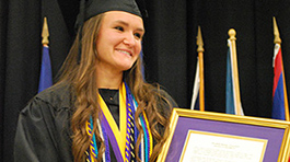 girl in graduation cap and gown with framed medal