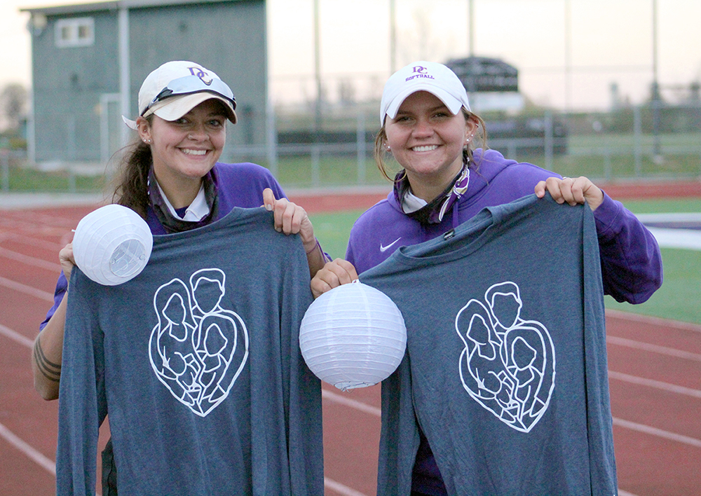 Two female students holding shirts up