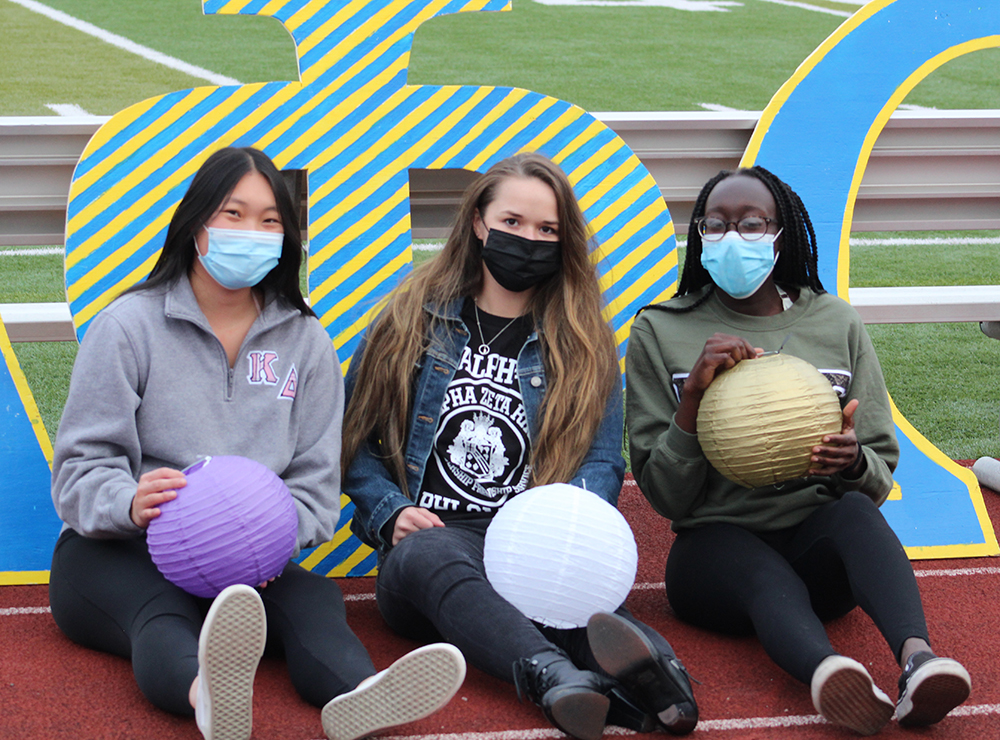 three students sitting with paper lanterns