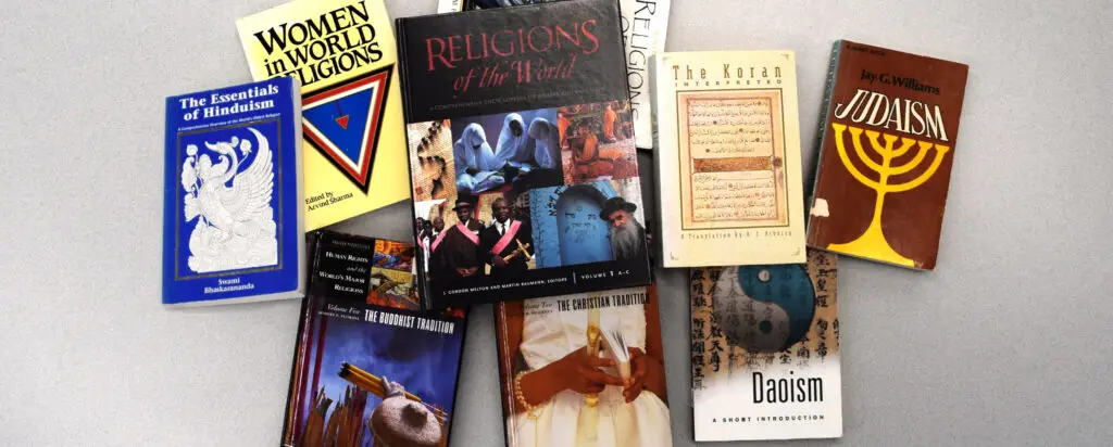 A variety of books about major world religions, including titles on Hinduism, Islam, Judaism, Daoism, and general world religions, are spread out on a light-colored surface.
